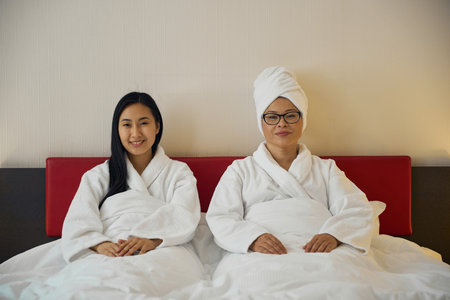 Joyous daughter and her mother resting in bedroom
