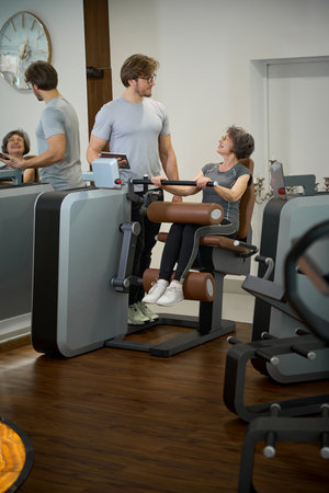 Trainer consulting elderly lady in the gym of fitness clinic