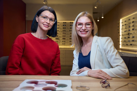 Two women with glasses are sitting at their desk