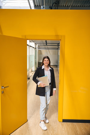 Girl with a laptop stands in the doorwayの写真素材