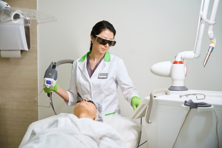 Young woman adjusts a modern laser device for operationの写真素材