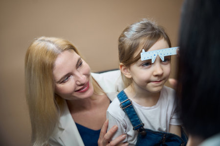 Ophthalmologist measures the distance between the eyes of little patient