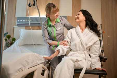Health worker helps a patient transfer from bed to wheelchairの写真素材