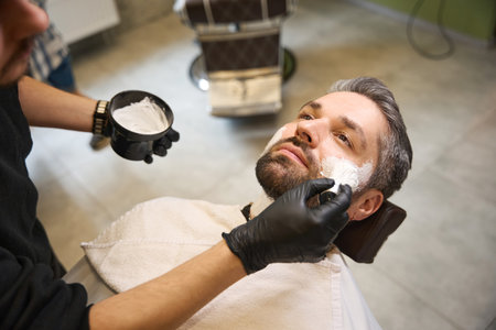 Bearded man visiting professional barbershop, lying on the chairの写真素材