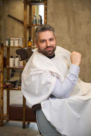 Handsome man with stylish haircut and beard posing looking at cameraの写真素材