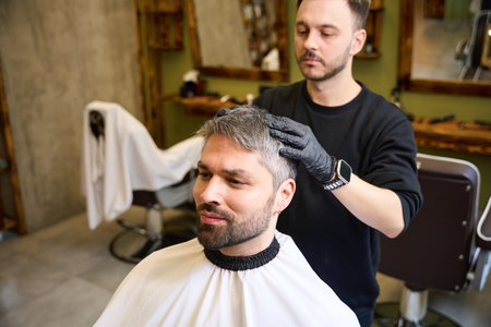 Experienced barber massaging adult clients head after the haircutの写真素材