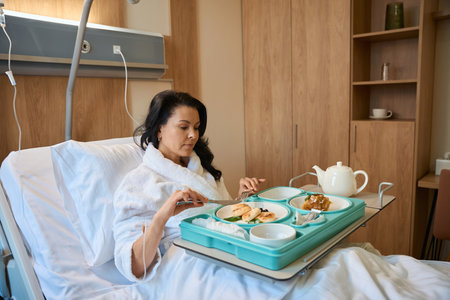 Woman with IV has breakfast in bedの写真素材
