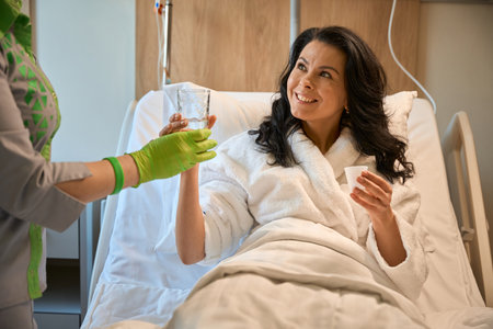 Nurse gives the patient a glass of waterの写真素材