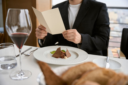 Close up of man in black suit having lunch, holding bill while sitting in the cafeの写真素材