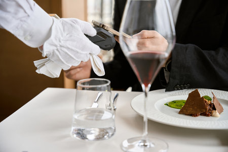 Man in black suit paying bill through mobile phone using NFC technology in restaurantの写真素材