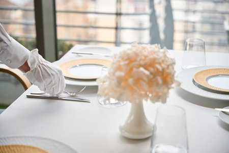Hand of male waiter in white glove setting a table in luxury restaurantの写真素材