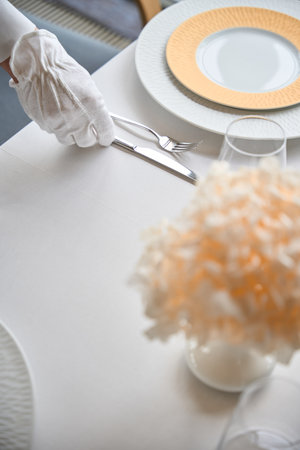Top view of waiter hand in white glove setting a table in modern restaurantの写真素材