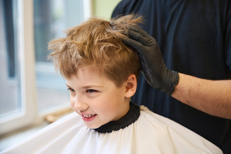High-qualified barber modeling little boy hairstyle using hair molding creamの写真素材