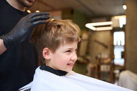 Hairdresser molding the hairstyle of little boy using special gelの写真素材