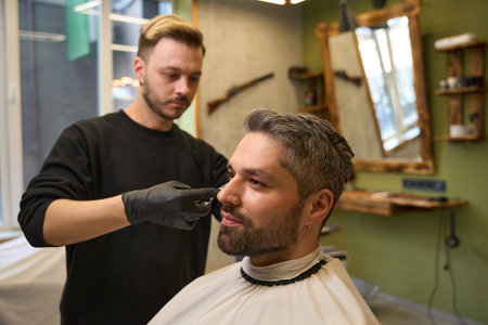 Focused hair stylist using professional scissors to make elegant haircutの写真素材