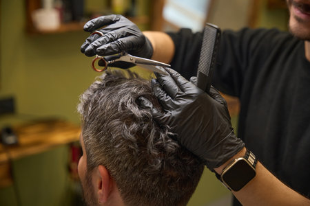 Skilled barber finishing mature man haircut cutting some hair endsの写真素材