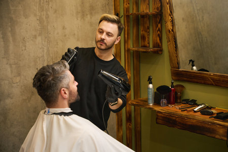 Barber looking at client face modeling forelock, applying fixing sprayの写真素材