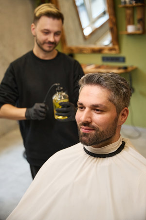 Self-confident man sitting at barber chair looking at reflection in mirrorの写真素材