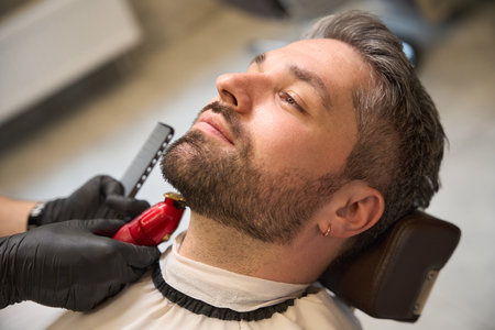 Man with stylish haircut waiting barber trimming neckline, modeling his beardの写真素材