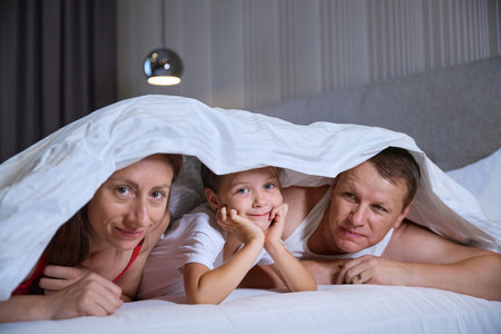 Married couple with little daughter in hut made of blanketsの写真素材