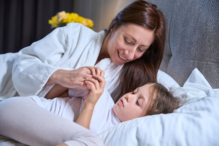 Mom wakes up her little daughter in the morningの写真素材