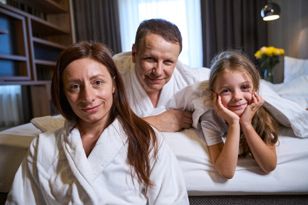 Couple with a small daughter are relaxing in hotel roomの写真素材