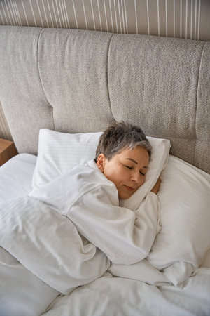 Top view of beautiful adult woman sleeping in hotel roomの写真素材