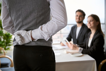 Waiter holds his hand behind his back while taking an order from a young couple