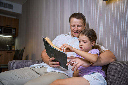 Father reading a book to his little daughterの写真素材