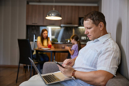 Man uses modern gadgets sitting in hotel roomの写真素材