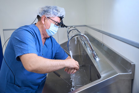 Doctor in mask cleaning hands before surgeryの写真素材