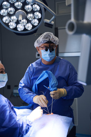 Surgeon examining patient data on monitor during surgeryの写真素材