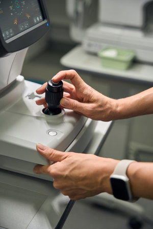 Optometrist adjusting eye examination equipment controlsの写真素材