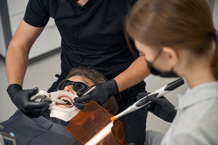 Patient lies in dentists chair wearing protective dark glassesの写真素材