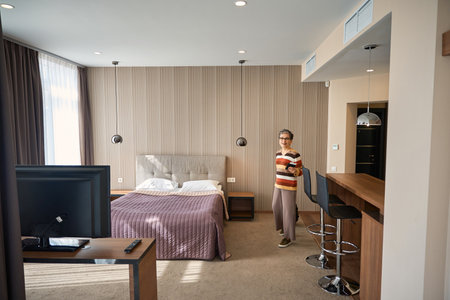 Adult woman with baggage and travel documents looking around hotel roomの写真素材