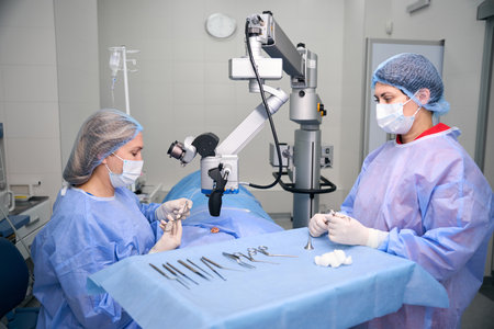 Female surgeon with assistant performing surgery in operating roomの写真素材