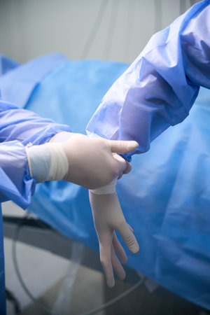 Medical staff help a doctor put on a surgical uniform
