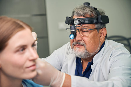 Male doctor assessing ear with focused attentionの写真素材