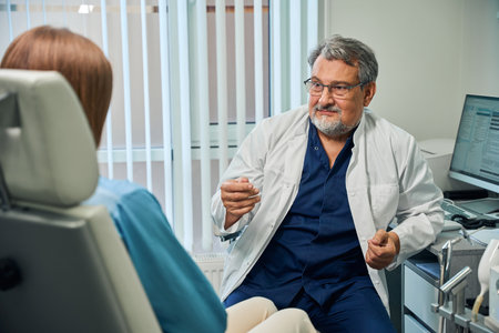 Elderly doctor gesturing during patient consultationの写真素材