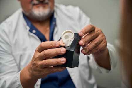Male doctor demonstrating a hearing aid to the patient