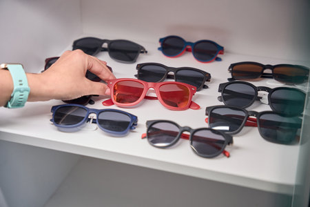 Female caucasian hand selecting glasses from displayの写真素材