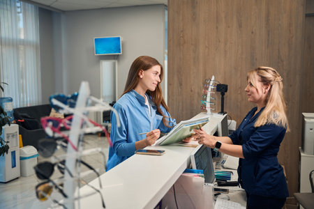 Patient and receptionist discussing paperwork at the counterの写真素材