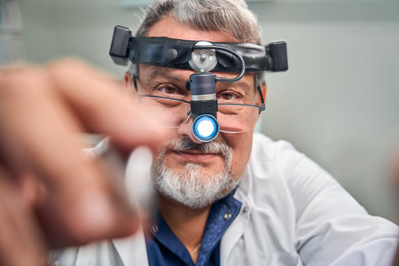 Doctor adjusting medical headlamp for eye examinationの写真素材