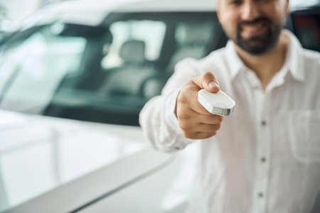 Smiling man showing car key at the dealership showroomの写真素材