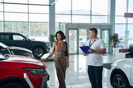 Salesman manager in formal wear helping female customer with choice of the carの写真素材