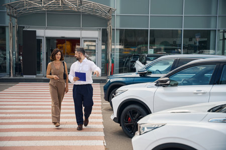 Woman and salesman manager walking near new cars outdoorsの写真素材