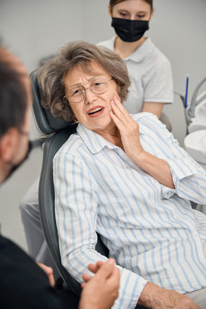 Woman at a doctors appointment complains to specialist about toothacheの写真素材