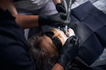 Patient lies in a dentists chair wearing protective dark glassesの写真素材