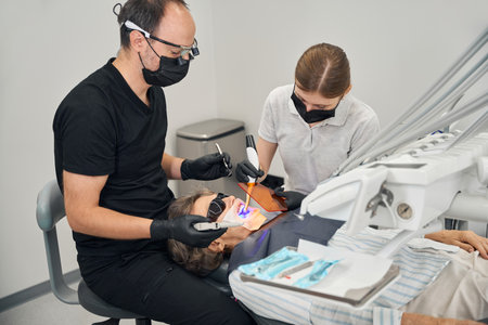 Doctor and an assistant put a photopolymer filling on patientの写真素材