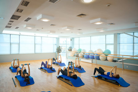 Ladies perform strength exercises with dumbbells, lying on special platformsの写真素材